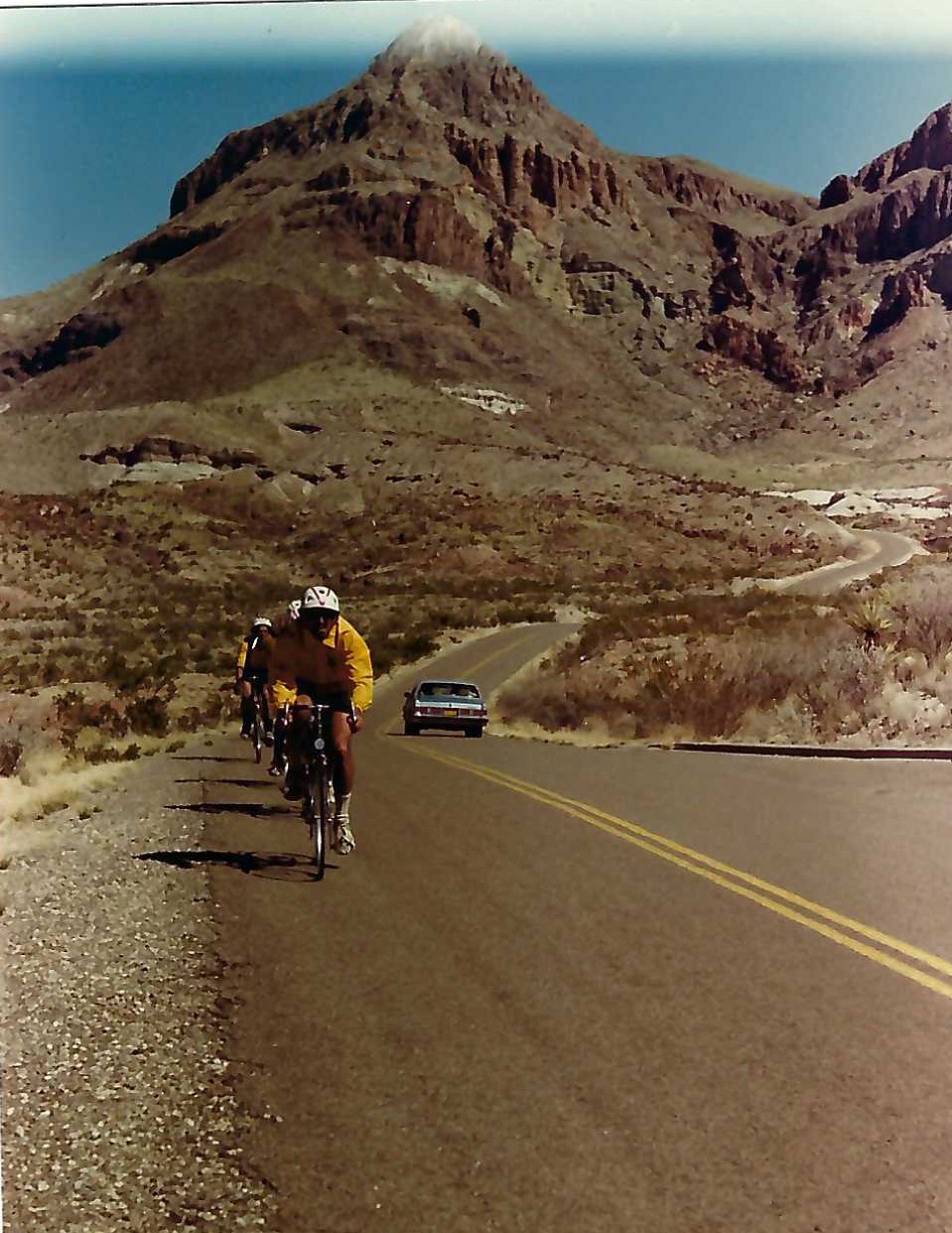 A man riding his bike down the side of a road.