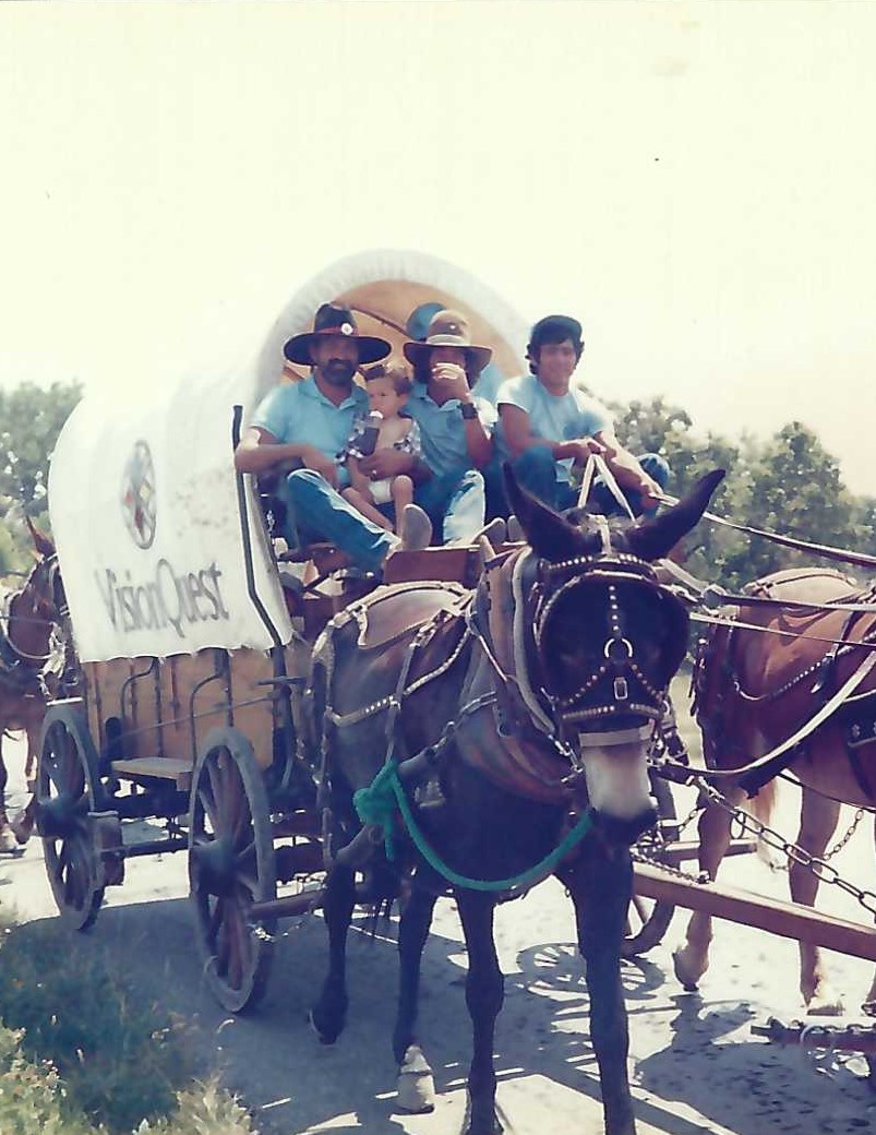 A group of people riding on the back of a covered wagon.